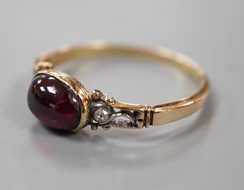 A 19th century yellow metal and single stone cabochon garnet set ring, with diamond chip set shoulders, size M, gross weight1.9 grams.